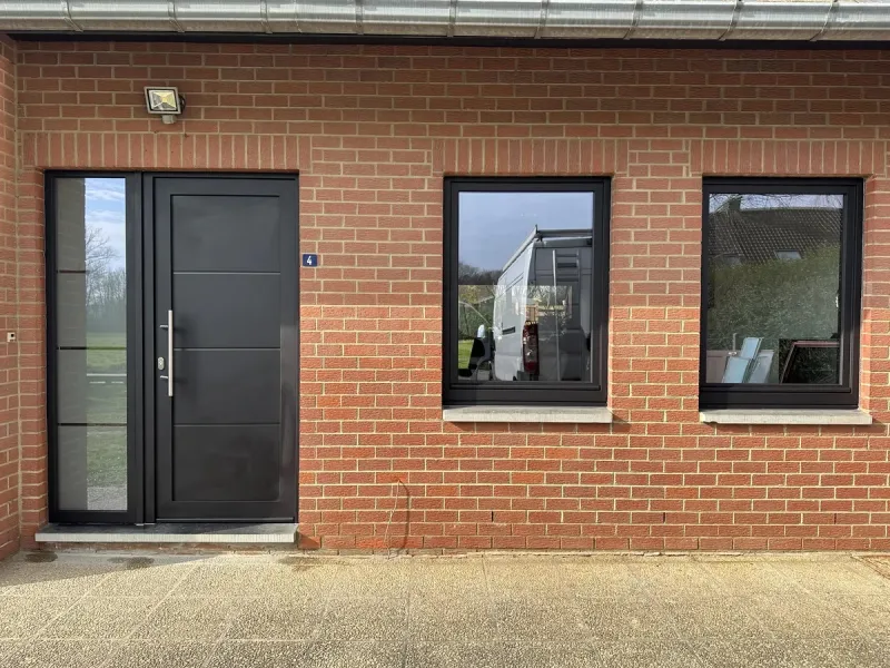 Porte et fenêtres en aluminium anthracite sur une façade en brique rouge, réalisation Menuiserie Bedetti à Gosselies