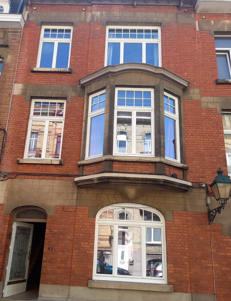 Châssis blancs à petits-bois posés sur le bow-window et la façade en brique d'une maison de maître bruxelloise, menuiserie soignée, par Andrex