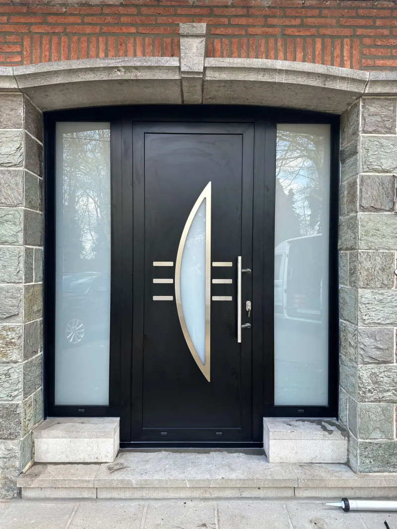 Porte d'entrée noire avec panneaux vitrés latéraux posée sous un arc en pierre sur une maison bruxelloise, réalisation ISME Home