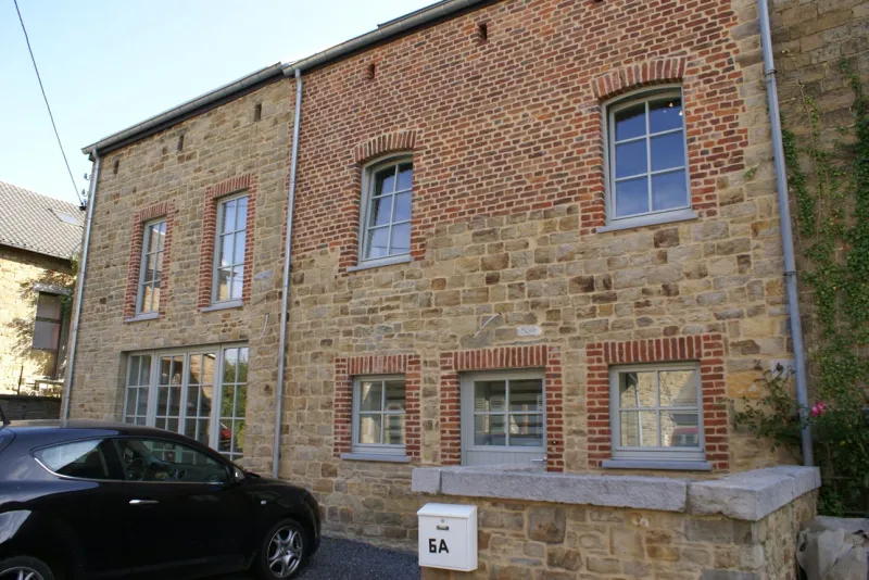 Fenêtres à petits-bois remplacées sur une façade ancienne en pierre et brique, en province de Liège, par Chassis 2000