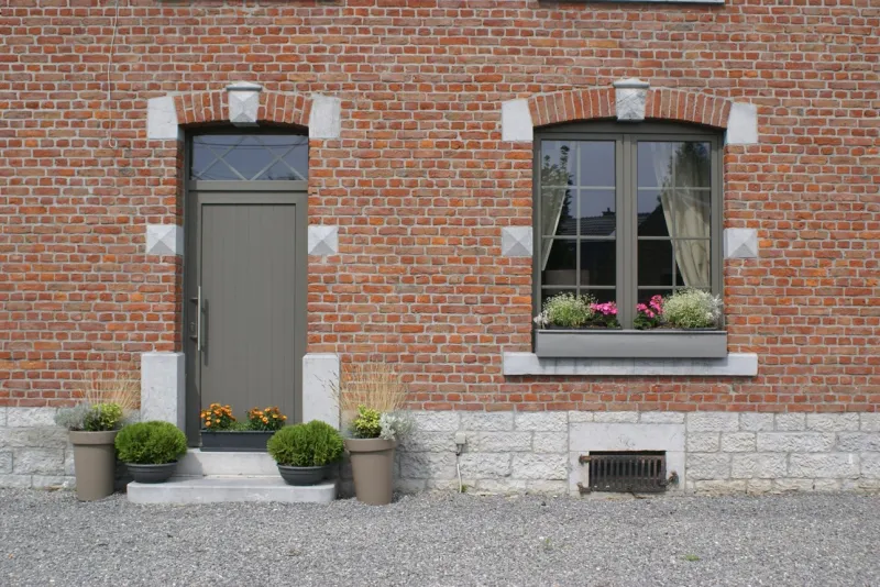 Porte d'entrée et fenêtre en menuiserie coordonnée sur une façade en brique, par Chassis 2000