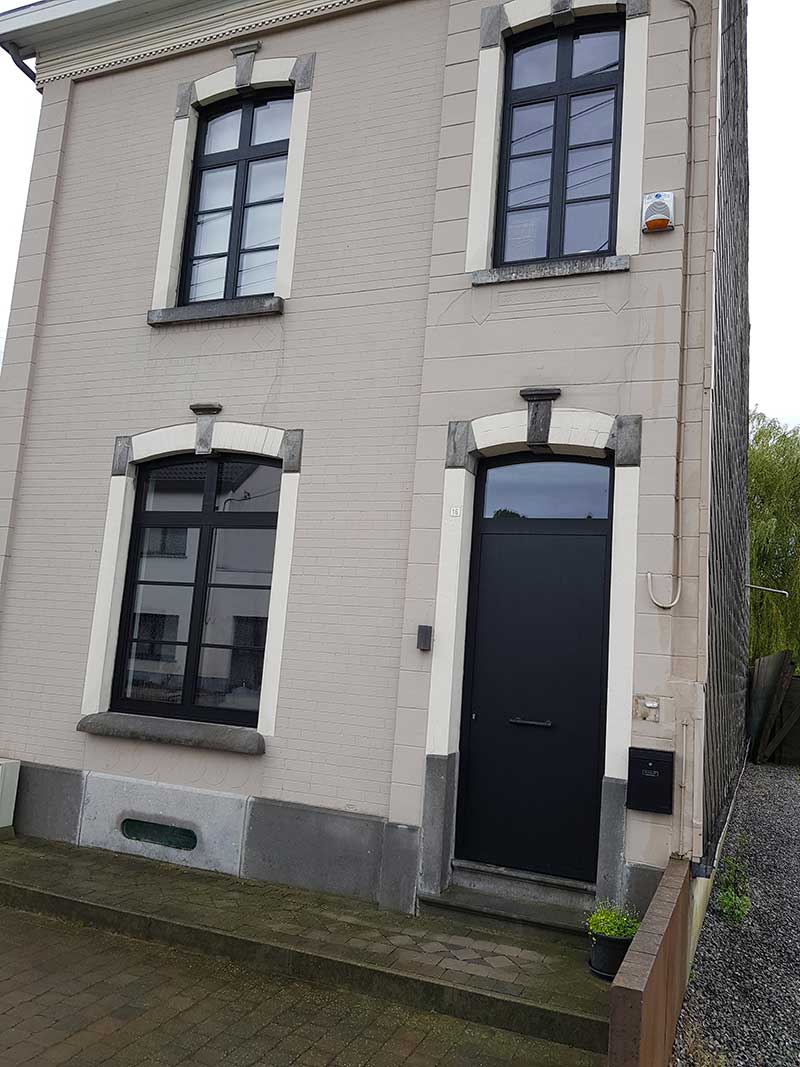 Fenêtres et porte d'entrée noires à arc surbaissé sur une maison enduite du Centre, réalisation Menuiserie Audain & Fils