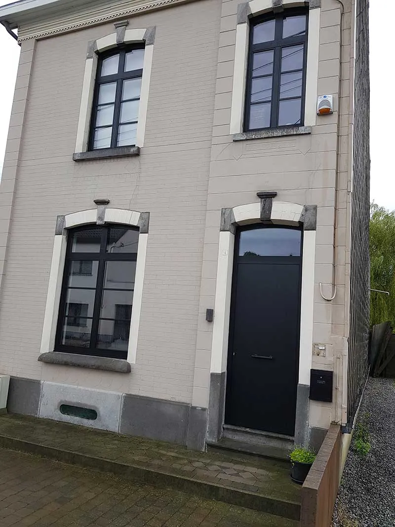 Fenêtres et porte d'entrée noires à arc surbaissé sur une maison enduite du Centre, réalisation Menuiserie Audain & Fils
