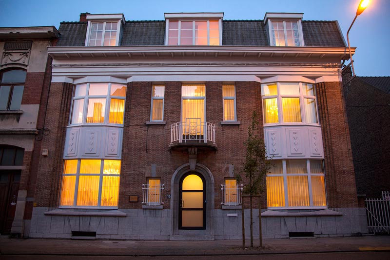 Façade en brique d'une maison de maître équipée de nombreux châssis blancs et bow-windows, réalisation Menuiserie Balasse à Manage