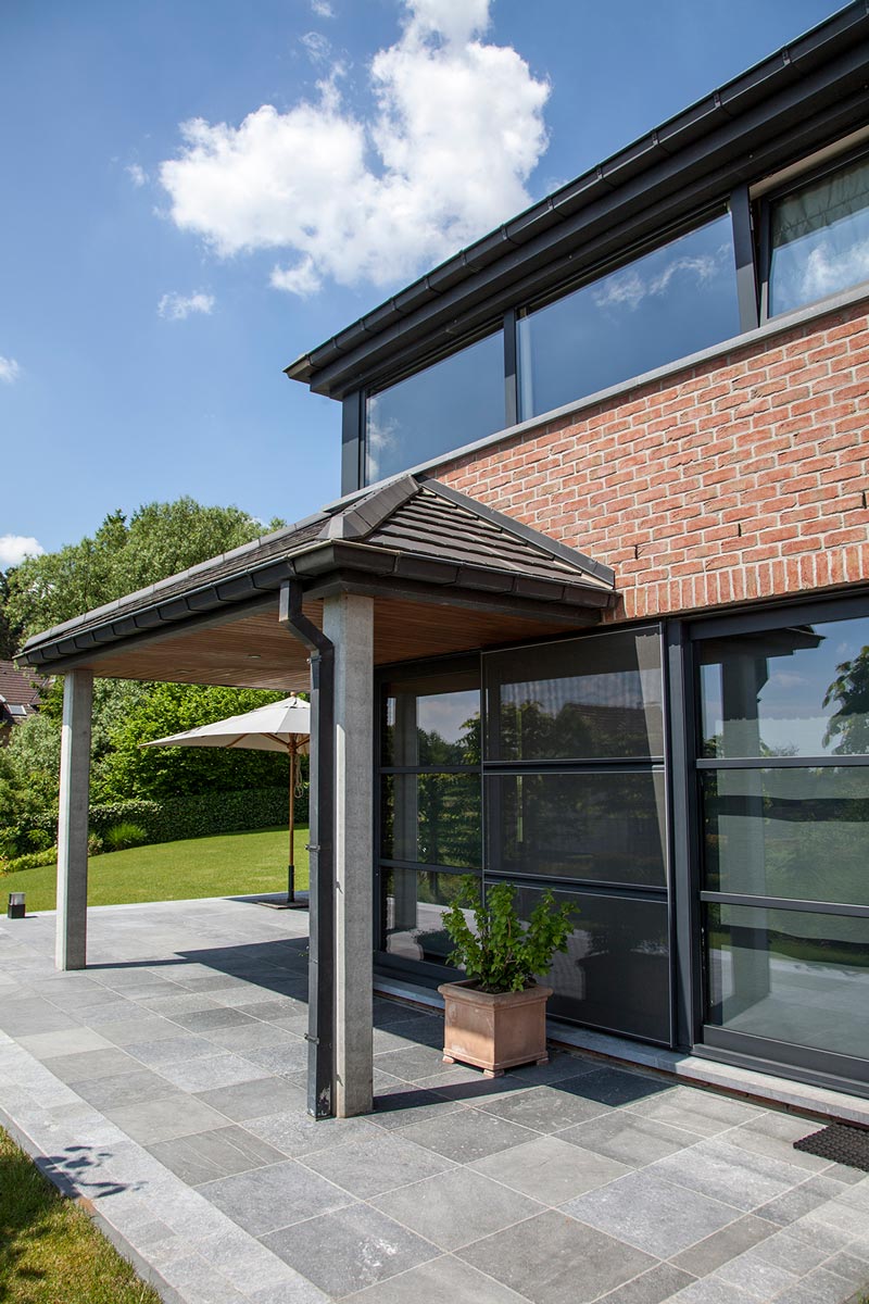 Grandes baies vitrées coulissantes en aluminium anthracite sur une maison contemporaine en brique, réalisation Menuiserie Balasse près de La Louvière
