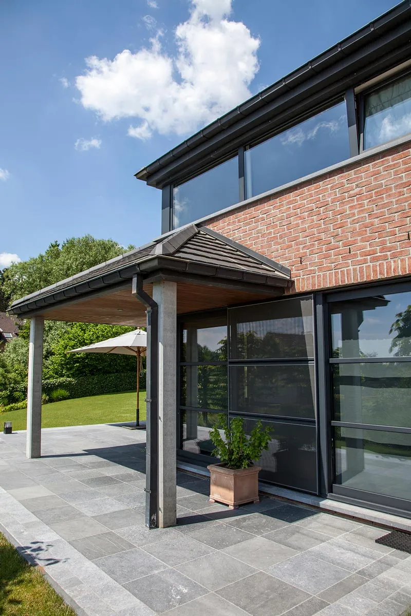 Grandes baies vitrées coulissantes en aluminium anthracite sur une maison contemporaine en brique, réalisation Menuiserie Balasse près de La Louvière