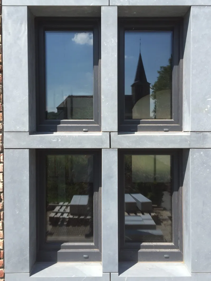Fenêtres anthracite encadrées de pierre bleue sur une maison de village namuroise, par MD Concept Home