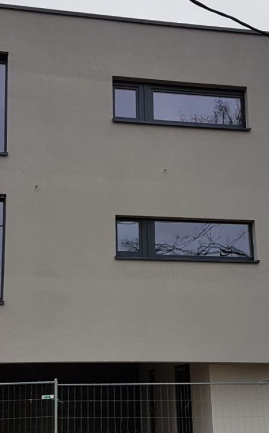 Fenêtres en aluminium anthracite sur une façade enduite, réalisation Mery Chassis près de Liège