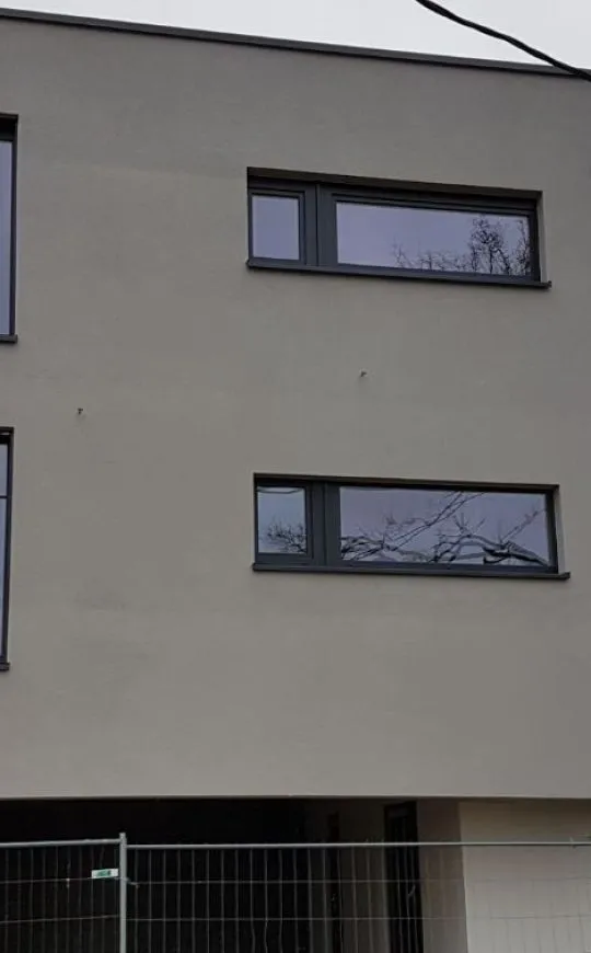 Fenêtres en aluminium anthracite sur une façade enduite, réalisation Mery Chassis près de Liège