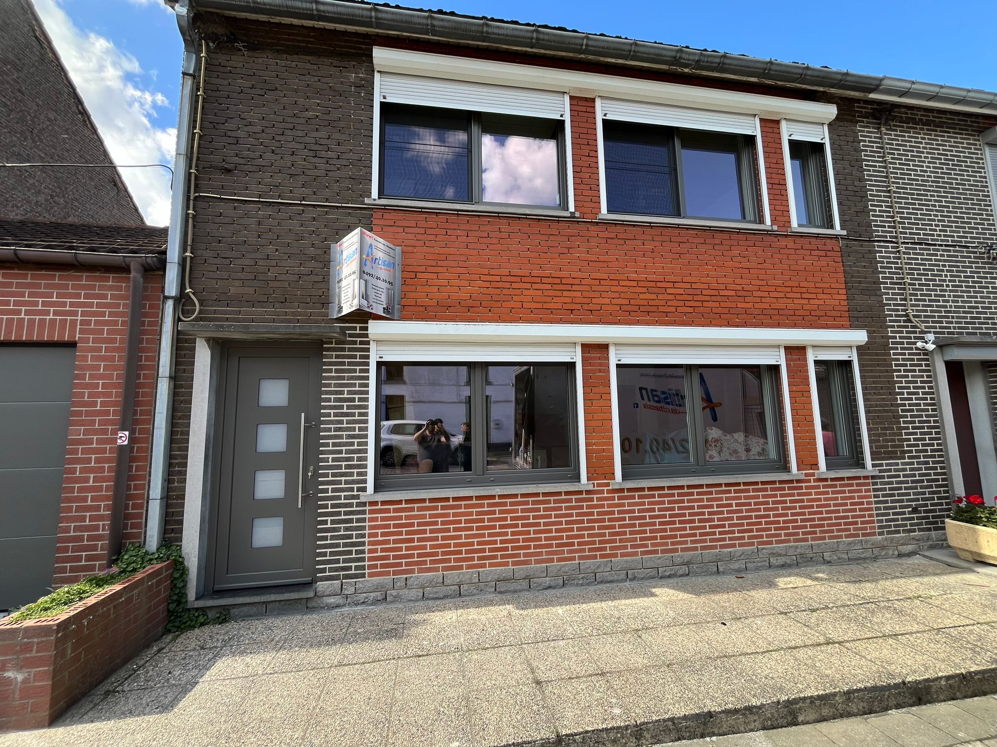 Fenêtres blanches en PVC et porte grise sur une maison en rangée en brique de la région de Mons, par Artisan du Châssis
