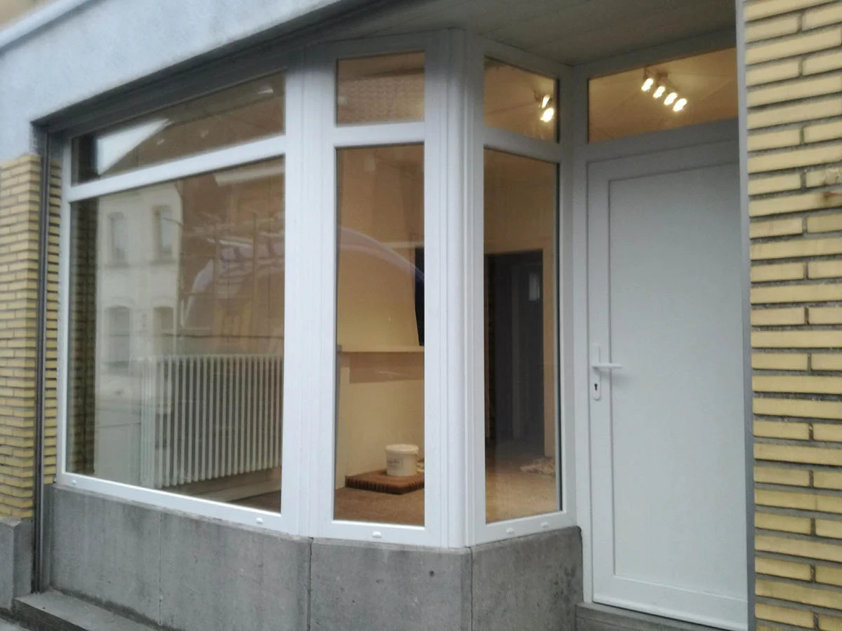 Grande fenêtre fixe et porte vitrée blanche en PVC posées sur une façade, réalisation Menuiserie Martin à Colfontaine