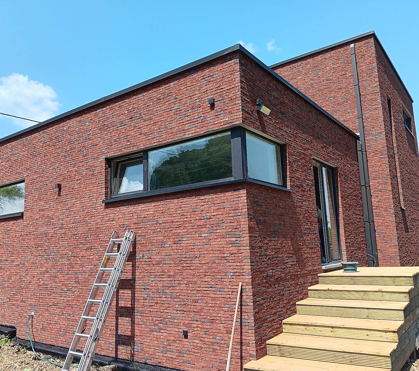 Fenêtres en aluminium anthracite sur une construction en brique rouge contemporaine, par Châssis Valency dans la région de Mons