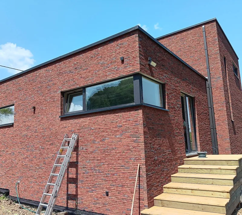 Fenêtres en aluminium anthracite sur une construction en brique rouge contemporaine, par Châssis Valency dans la région de Mons