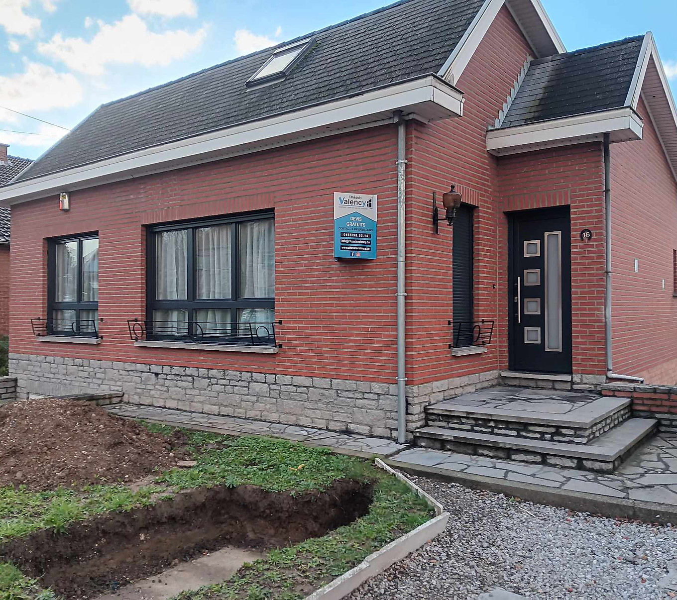 Châssis anthracite, volets et porte d'entrée sur une villa en brique rouge sur soubassement en pierre, réalisation Châssis Valency en Hainaut