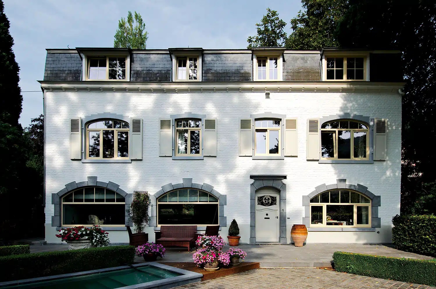 Nombreux châssis et porte sur une grande maison en brique peinte blanche, réalisation Maison Passion à Wépion