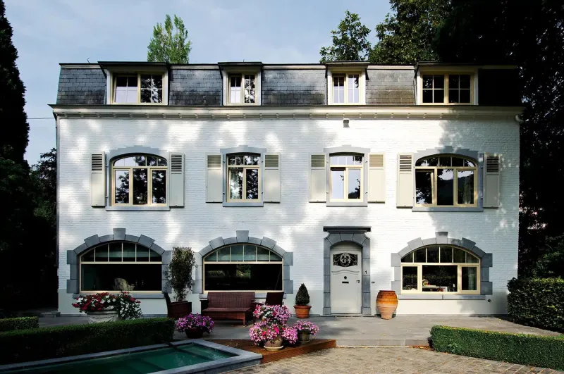 Nombreux châssis et porte sur une grande maison en brique peinte blanche, réalisation Maison Passion à Wépion