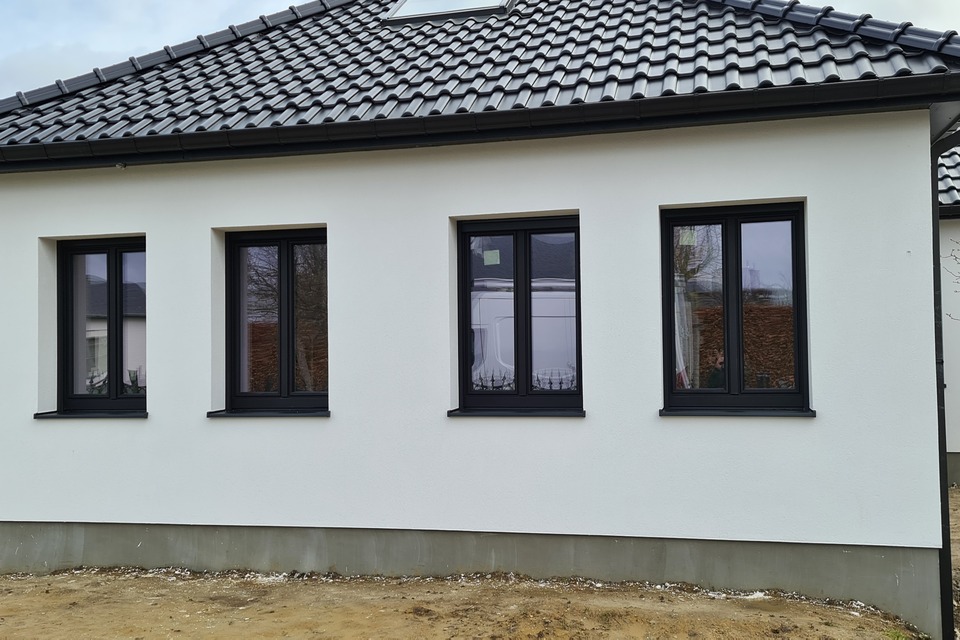 Quatre fenêtres en aluminium anthracite posées sur une façade blanche enduite près de Nivelles, réalisation BHB Windows