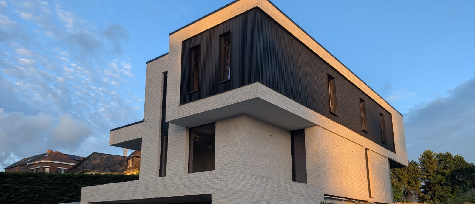 Fenêtres et baies en teinte foncée sur une villa contemporaine en brique blanche et bardage, réalisation Concepteo Châssis