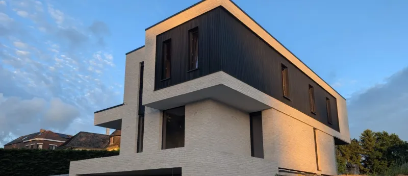 Fenêtres et baies en teinte foncée sur une villa contemporaine en brique blanche et bardage, réalisation Concepteo Châssis