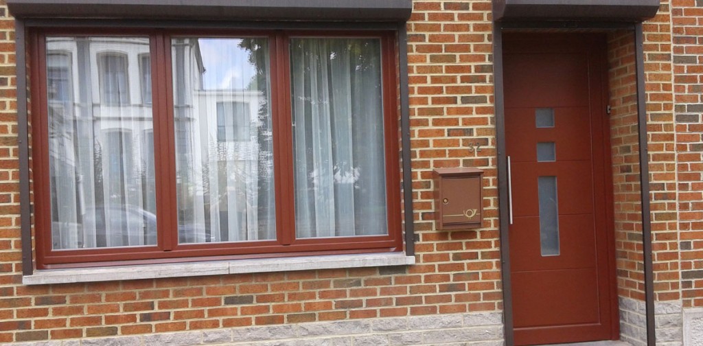Large fenêtre et porte d'entrée en teinte bordeaux coordonnées sur une façade en brique, réalisation Menuiserie Lambrechts à Nivelles