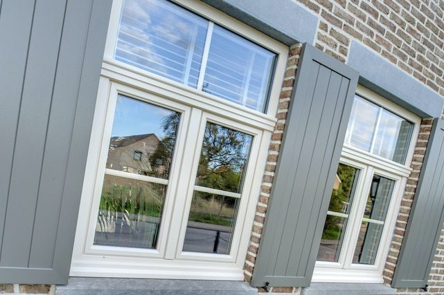 Fenêtres à frappe crème encadrées de bardage gris sur une façade en brique, réalisation Sio2 Châssis à Flémalle