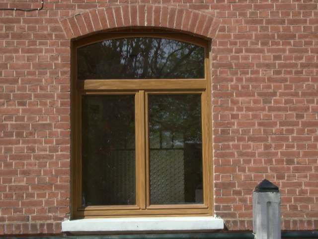 Fenêtre en bois cintrée posée sur une façade en brique rouge dans la région de Tournai, par L'Atelier de Menuiserie