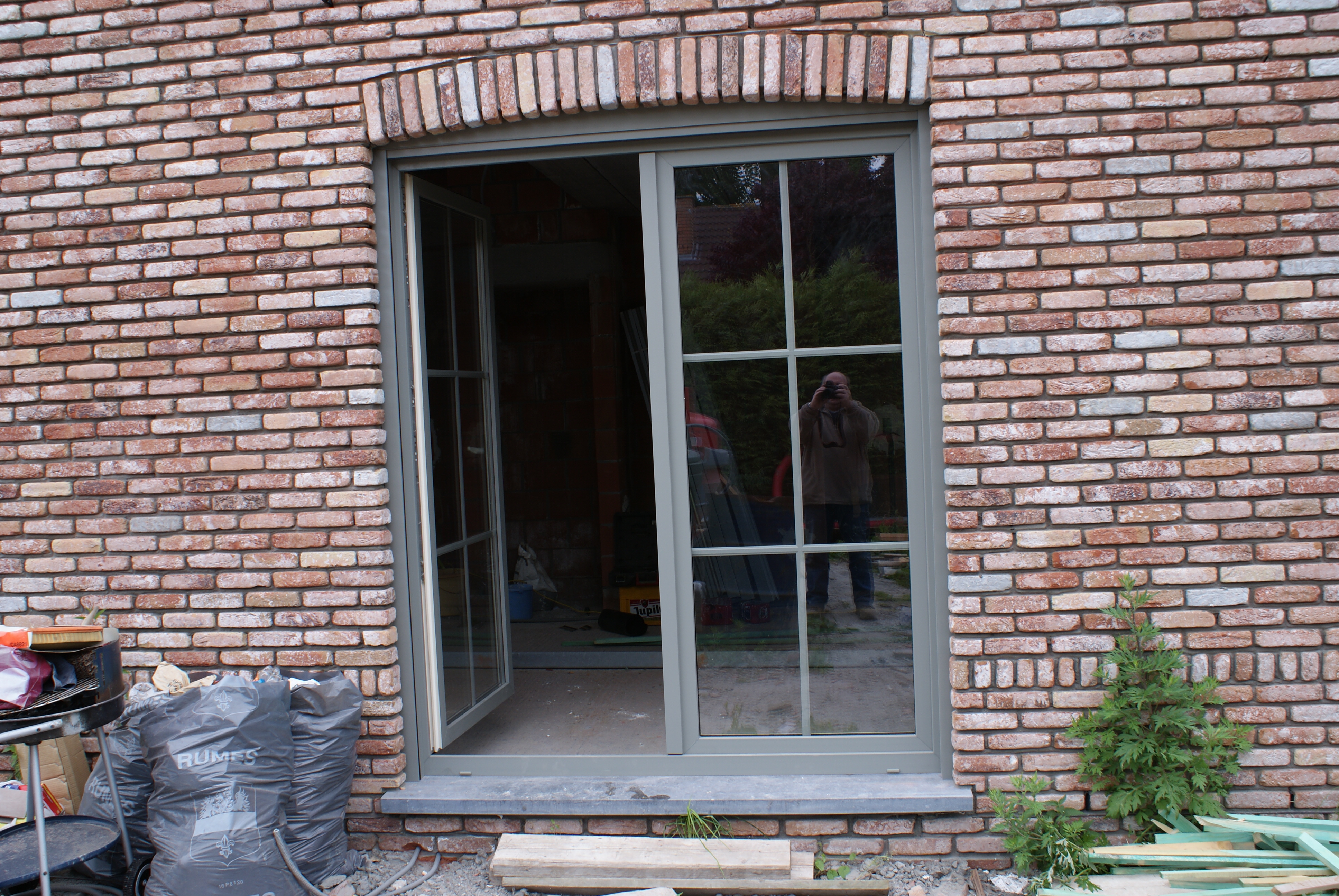 Châssis et porte-fenêtre gris à petits-bois posés sur une façade en brique en rénovation près de Tournai, par L'Atelier de Menuiserie