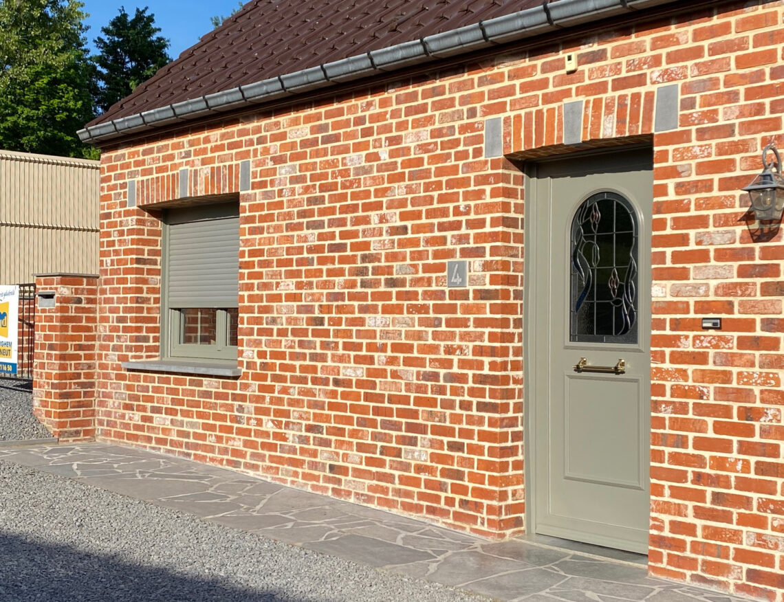 Porte d'entrée grise vitrée et fenêtre avec volet sur une maison en brique à Tournai, réalisation Menuiserie Morlighem - Decneut