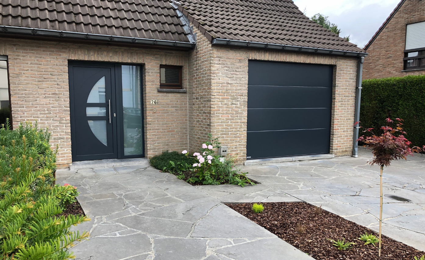 Porte d'entrée anthracite avec hublot vitré et fenêtre sur un bungalow en brique claire à Tournai, réalisation Menuiserie Morlighem - Decneut