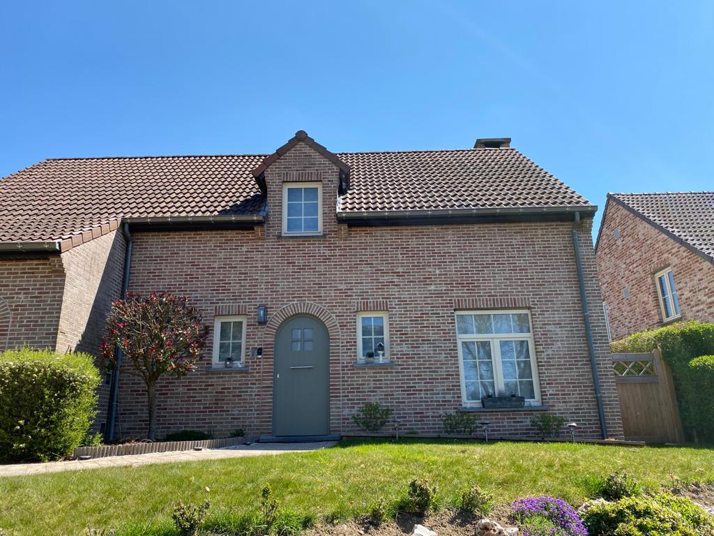 Fenêtres en PVC blanc et porte d'entrée cintrée sur une villa 4 façades en brique du Brabant wallon, par Idées Portes & Châssis