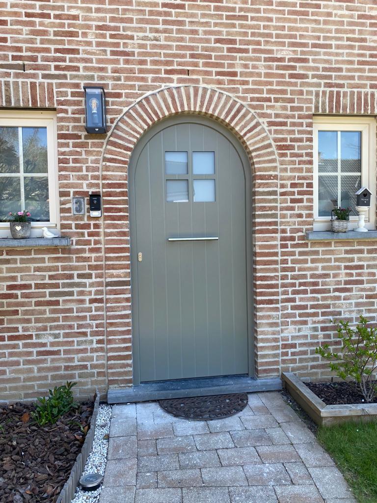 Porte d'entrée cintrée vitrée et fenêtres en PVC blanc encadrées de brique, réalisation Idées Portes & Châssis dans le Brabant wallon