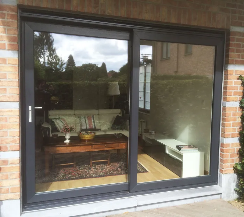 Grande baie coulissante en aluminium anthracite posée dans une façade en brique, réalisation Nikal Châssis en Brabant wallon