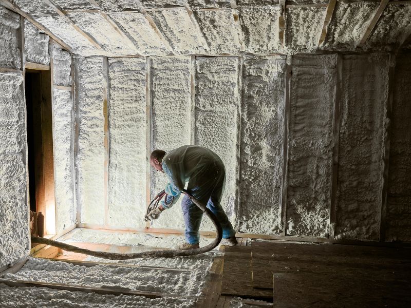 Application de mousse polyuréthane projetée sur les murs d'une pièce en rénovation