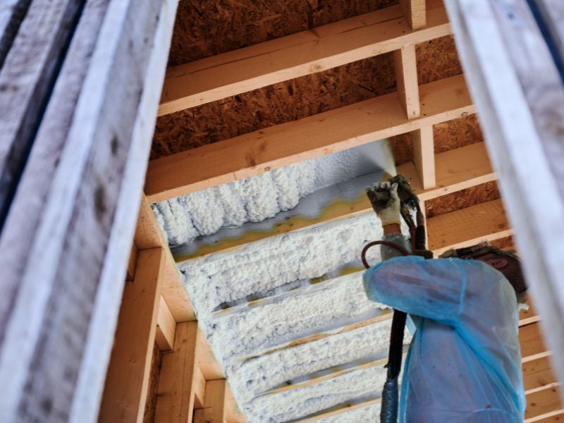Projection de mousse PUR sous un plancher en bois lors d'un chantier d'isolation