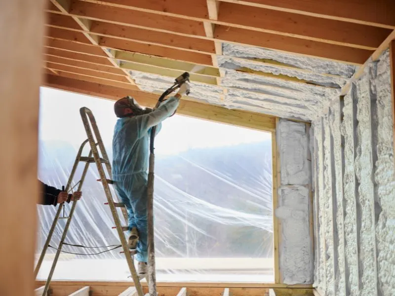 Isolation par projection de polyuréthane autour d'une baie vitrée en cours de chantier