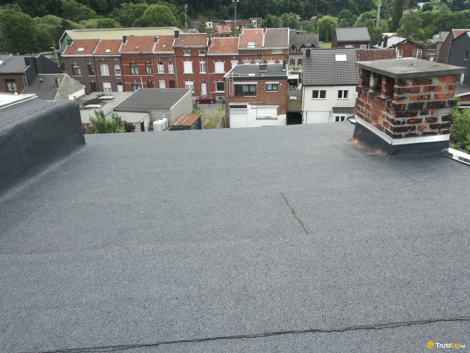 Vue panoramique sur les toits depuis une toiture plate en réfection avec souche de cheminée, par ARS Concept à Seraing
