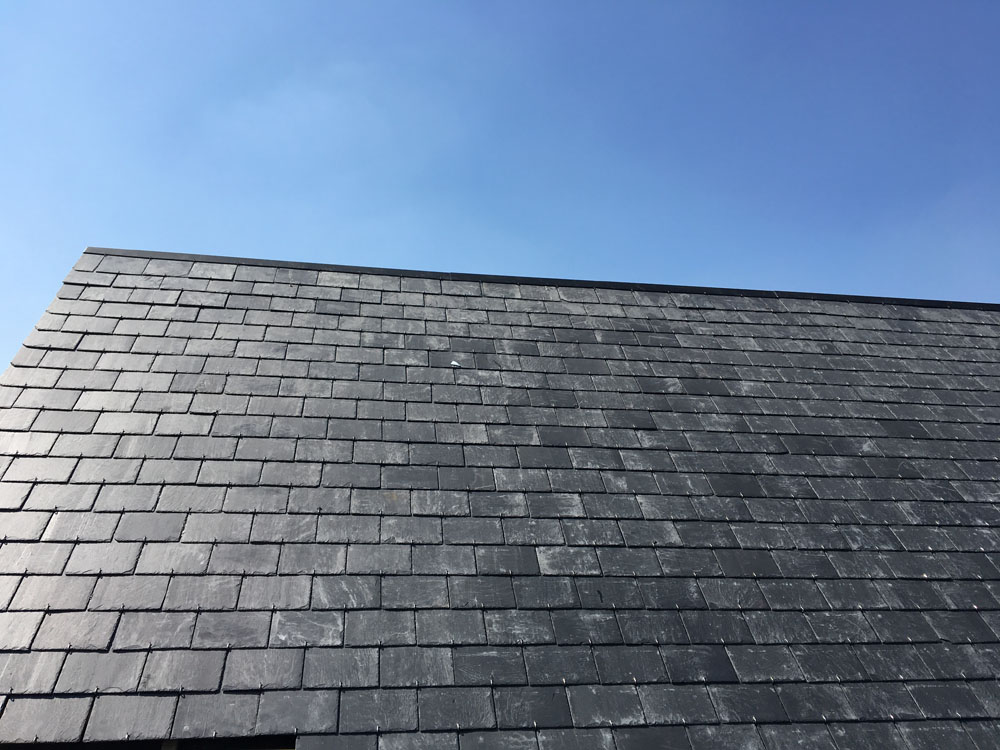 Versant de toiture en ardoises naturelles sous un ciel bleu, par Les Couvertures Dassonville