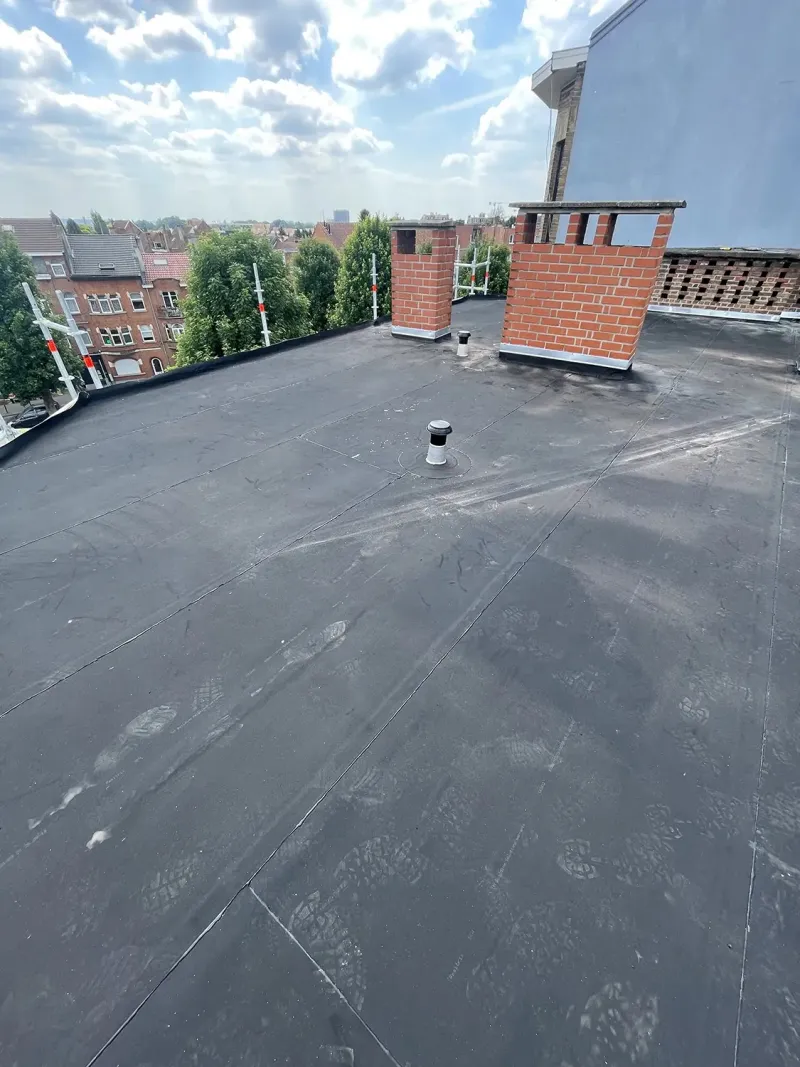Toiture plate en EPDM avec souches de cheminée et vue sur les toits bruxellois, par Delta-X Toitures