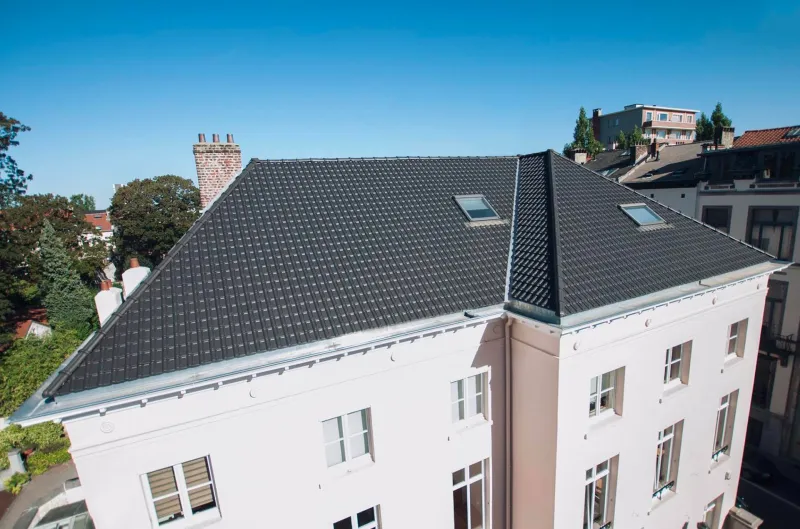 Toiture en tuiles émaillées noires avec fenêtres de toit et vue sur les toits bruxellois, par Toiture DIM