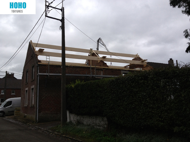 Charpente en bois neuve levée à la grue sur une maison en briques par HoHo Toitures