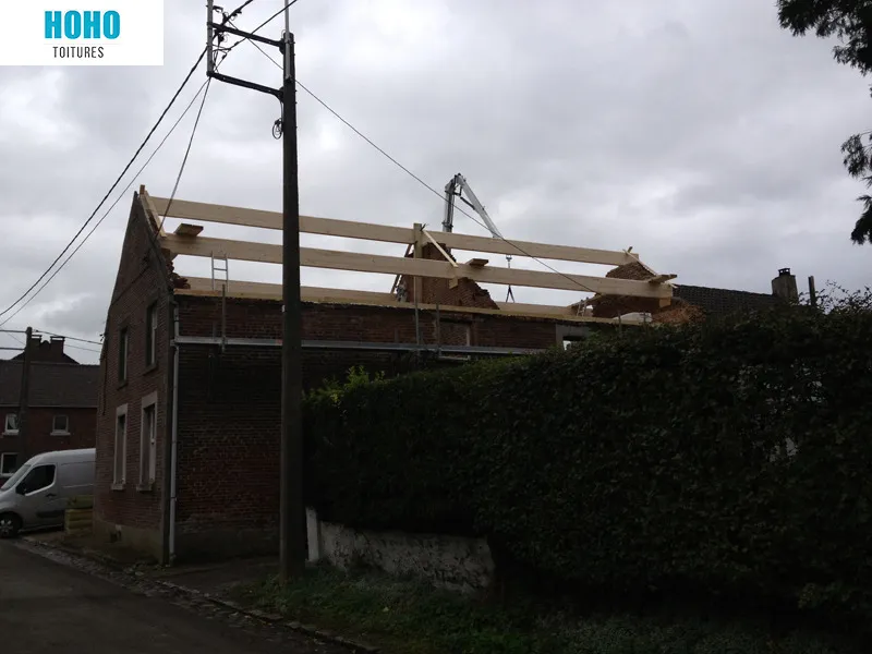 Charpente en bois neuve levée à la grue sur une maison en briques par HoHo Toitures