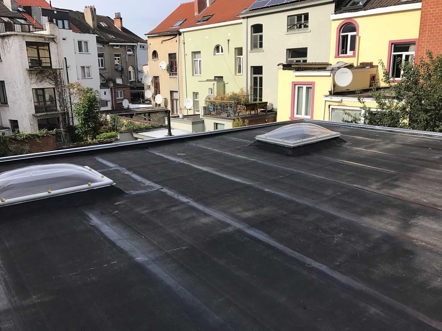 Toiture plate en EPDM avec coupoles et vue sur les maisons bruxelloises, par Toitures de Jette