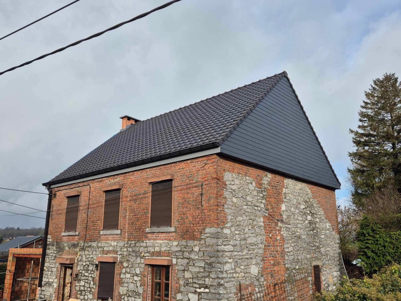Nouvelle toiture en tuiles sur une maison en briques réalisée par Toiture Roosens