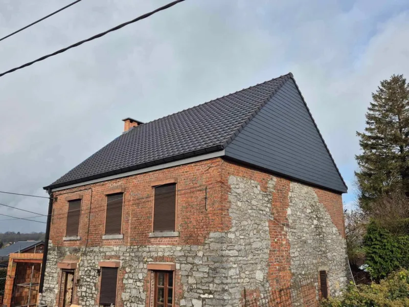 Nouvelle toiture en tuiles sur une maison en briques réalisée par Toiture Roosens