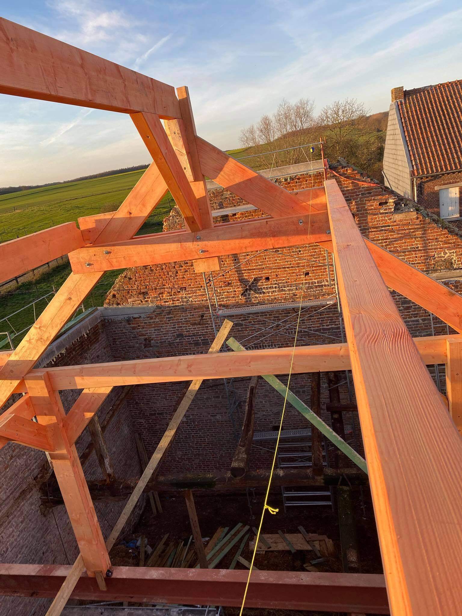 Charpente neuve en bois d'une toiture en construction au coucher du soleil, par Toit mon Toit