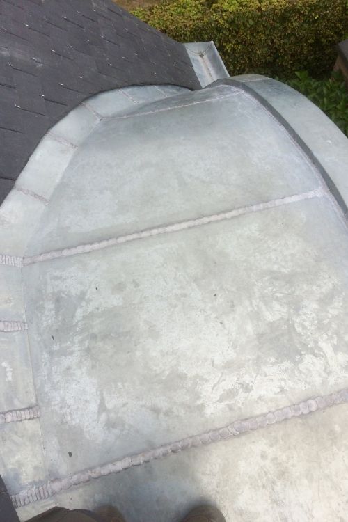 Habillage en zinc d'une baie arrondie sur une toiture schaerbeekoise, par Toitures Yakubs