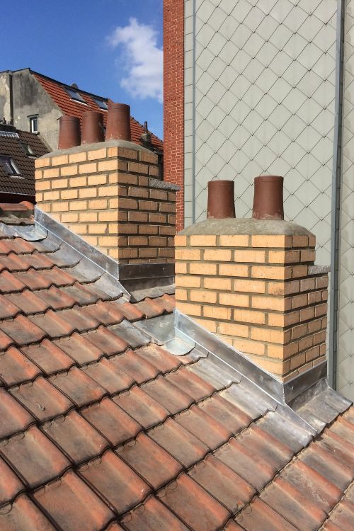Toiture en tuiles neuve avec zinguerie et souches de cheminée, vue sur Schaerbeek, par Toitures Yakubs