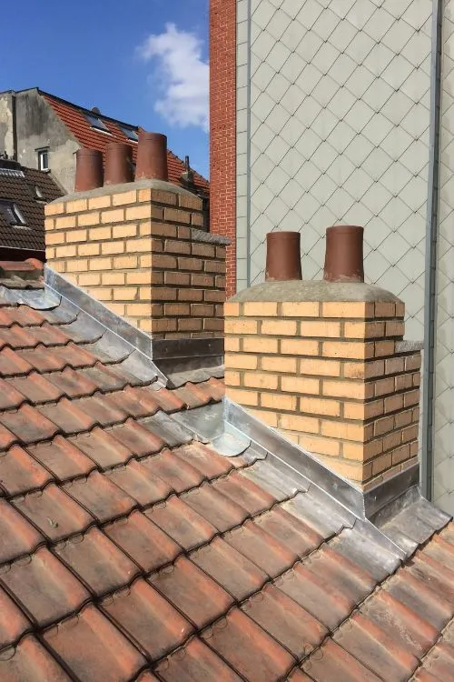 Toiture en tuiles neuve avec zinguerie et souches de cheminée, vue sur Schaerbeek, par Toitures Yakubs